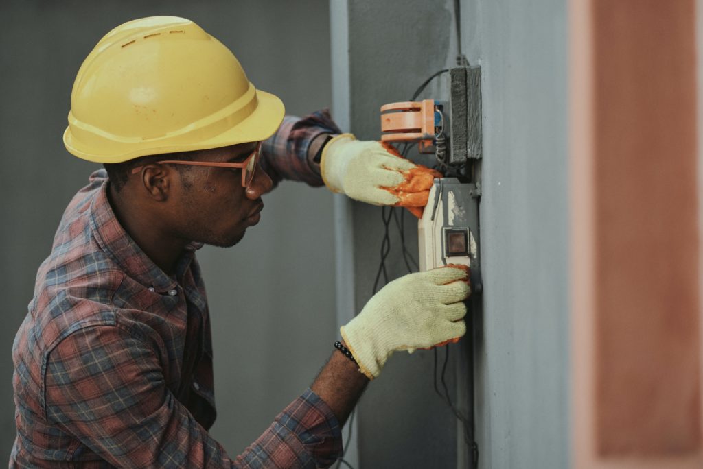 Male in construction gear rewiring an electrical box
